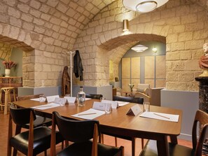 A conference room with a brick wall, wooden table, black chairs, and a bust sculpture. - Mercure Paris Notre Dame Saint Germain des Prés (Paris)