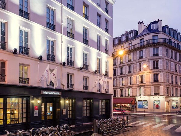 Un hôtel à la façade classique, doté de nombreux balcons et où l’on peut voir une rangée de vélos garés à l’extérieur.