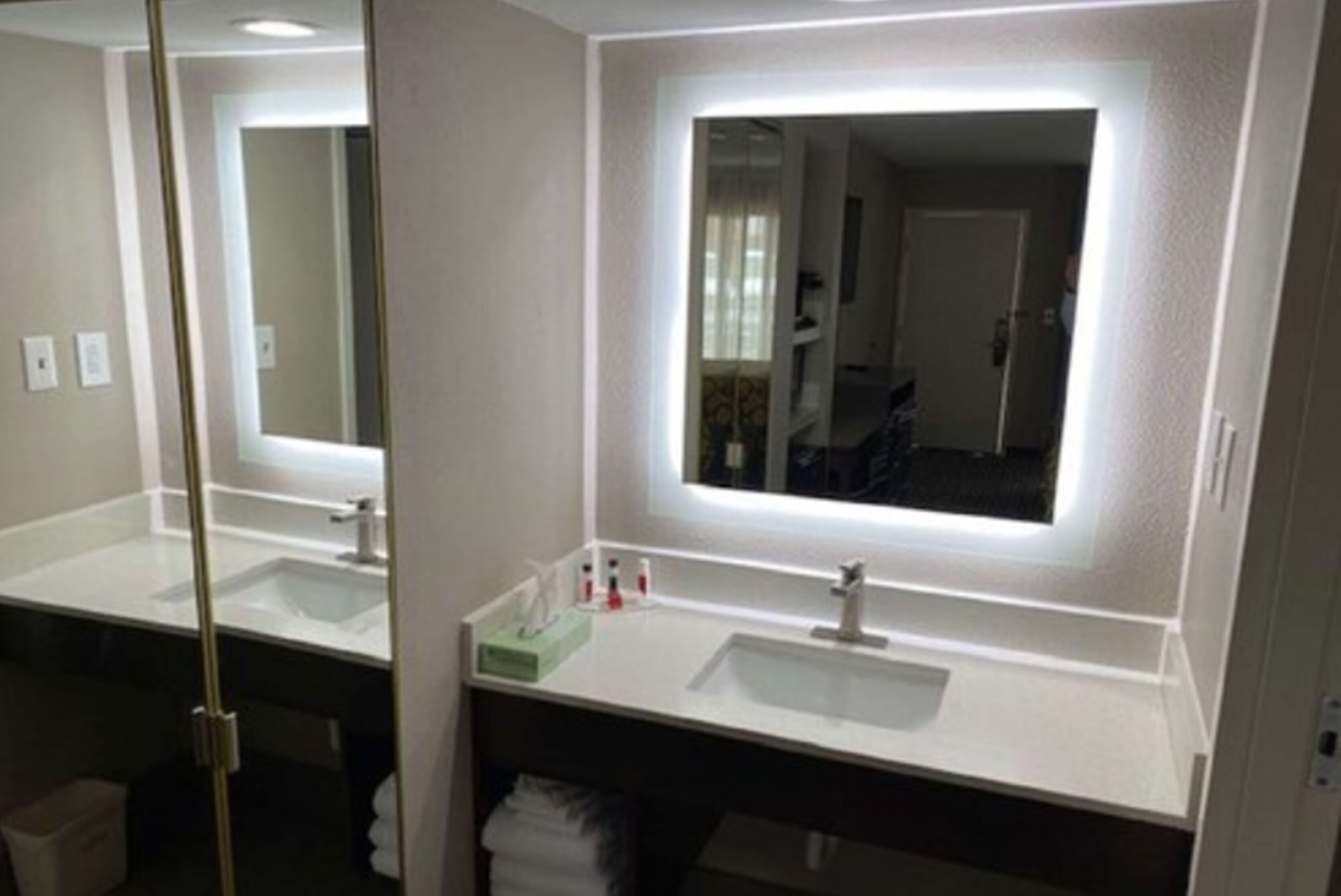 Une salle de bain avec deux lavabos, un miroir et un porte-serviettes.