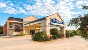 A hotel entrance with a sign reading 'Baymont Suites,' a covered parking area, and a clear sky. - Baymont by Wyndham Topeka (Topeka)