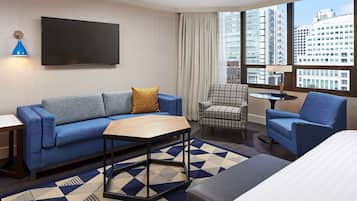 A modern hotel room with a sofa, armchair, and a small table.
