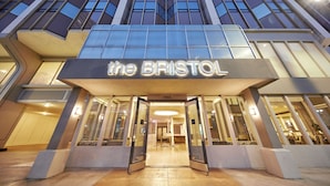 The exterior of The Bristol hotel with a modern facade, large glass windows, and a prominent entrance.