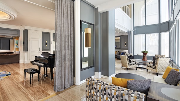 A spacious living area with a grand piano, comfortable seating, and large windows providing natural light.