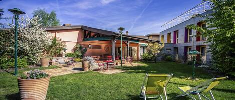 Un patio con césped, mobiliario exterior y un edificio con un porche cubierto.