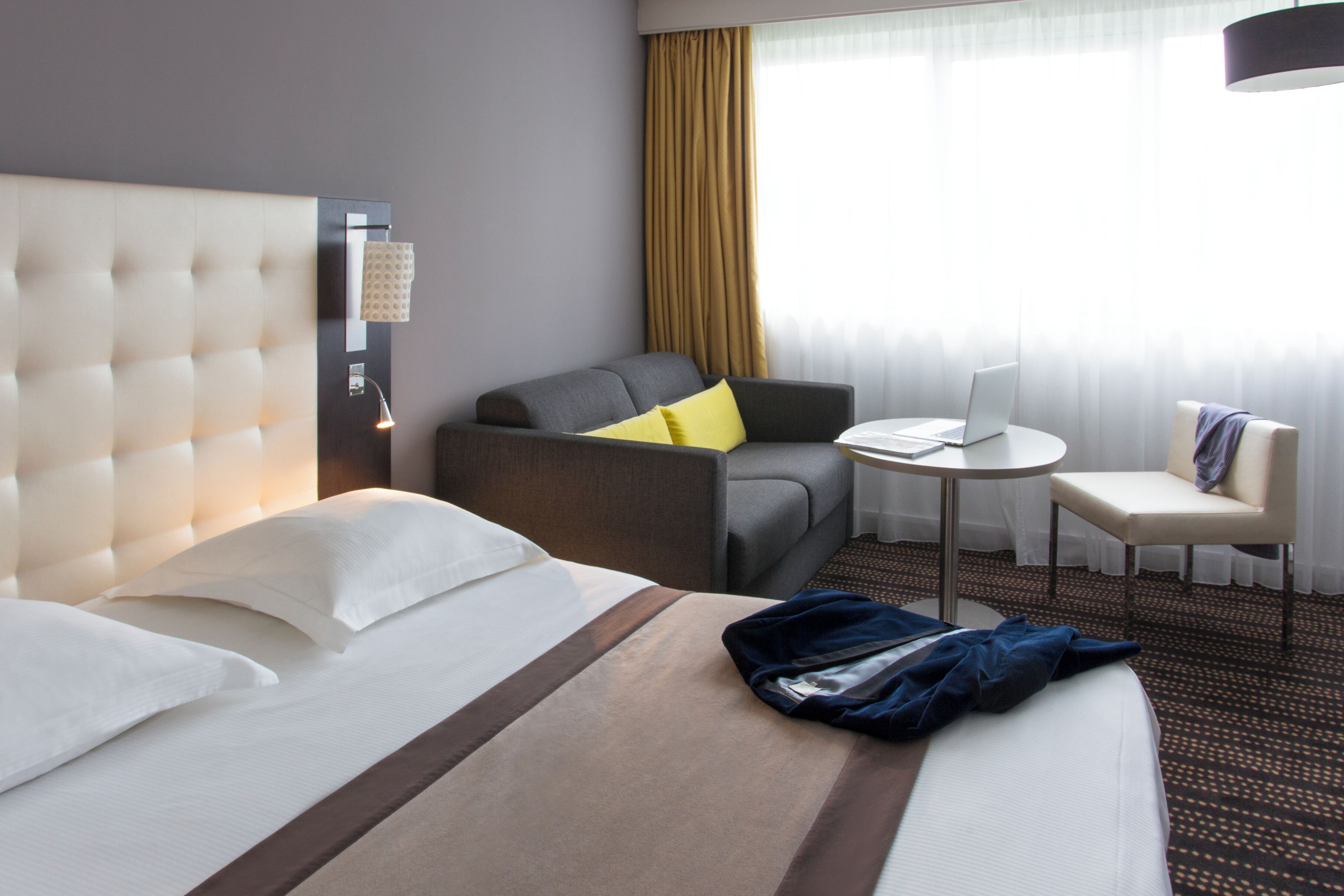 Een hotelkamer met een groot bed, een slaapbank, een tafeltje en een stoel.