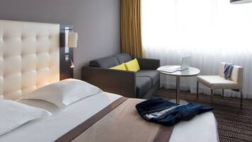 Een hotelkamer met een groot bed, een slaapbank, een tafeltje en een stoel.