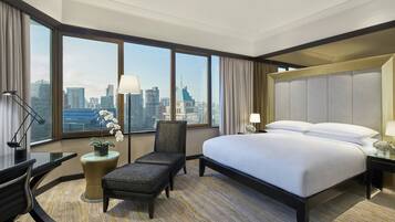 Une chambre d’hôtel avec un grand lit, un bureau, une chaise et une vue sur le paysage urbain.