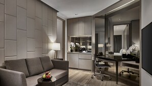 A modern hotel room with a sofa, a small table with fruit, a desk with a chair, a kitchenette, and a large mirror. - Singapore Marriott Tang Plaza Hotel  (Singapore)