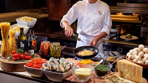 A chef preparing food in a kitchen with various ingredients and utensils visible. - Singapore Marriott Tang Plaza Hotel  (Singapore)