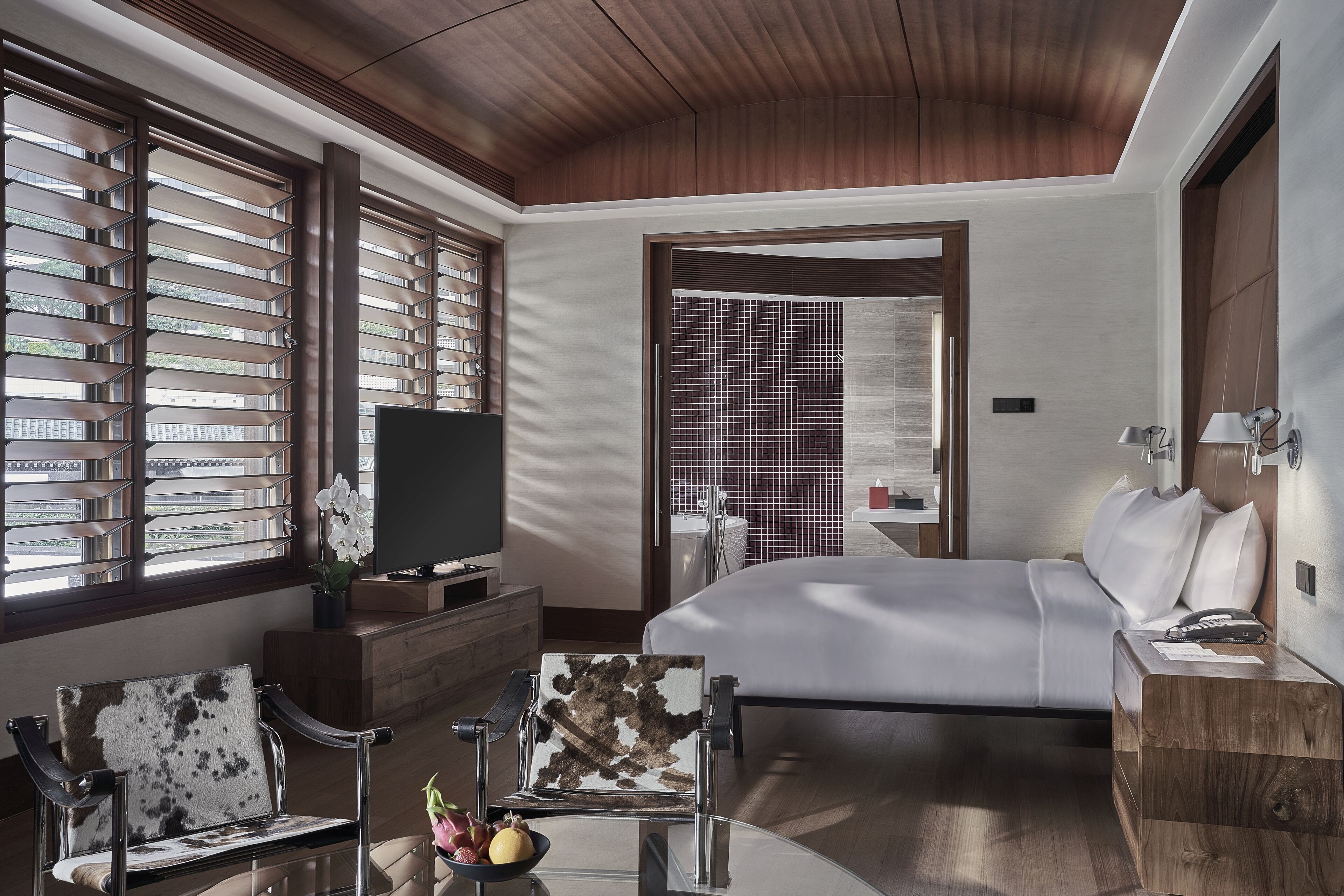 Una habitación de hotel moderna con una cama grande, televisión, escritorio y una silla.
