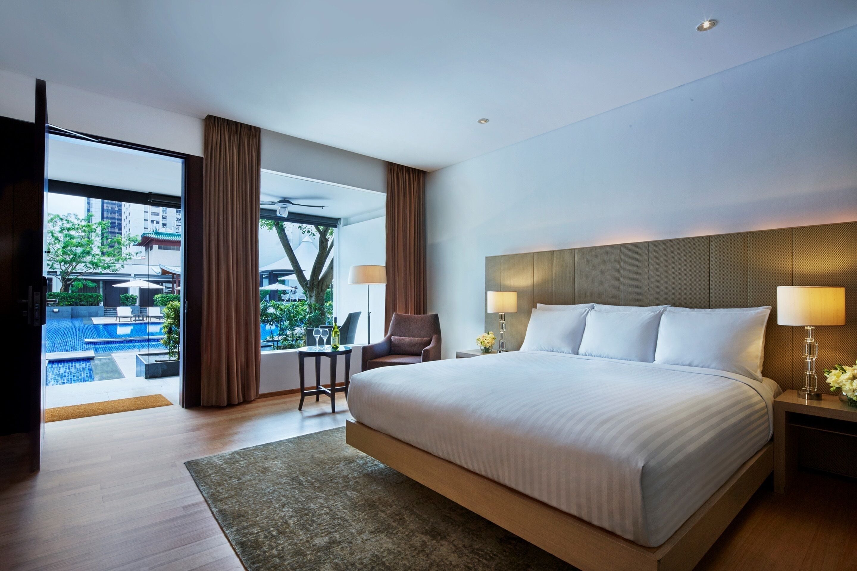 Une chambre d’hôtel moderne avec un grand lit, un bureau et une vue sur une piscine.