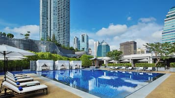 Una piscina al aire libre, sombrillas, sillones reclinables de piscina