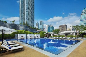 Una piscina al aire libre, sombrillas, sillones reclinables de piscina
