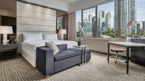 A modern hotel room with a large bed, a sofa, a desk, and a view of tall buildings. - Singapore Marriott Tang Plaza Hotel  (Singapore)
