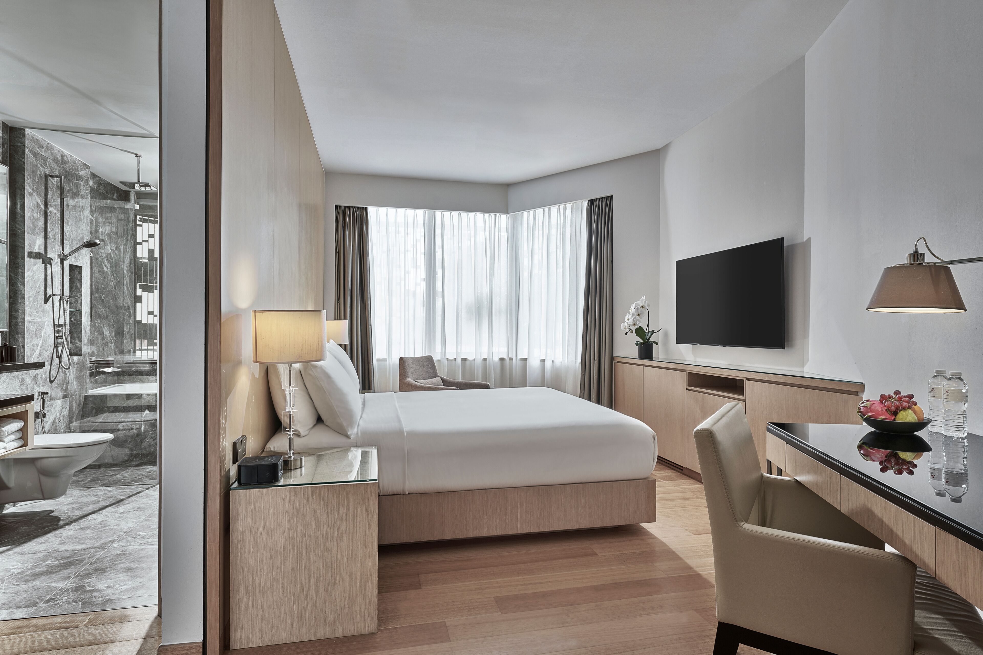 Una habitación de hotel moderna con cama, escritorio y televisor.