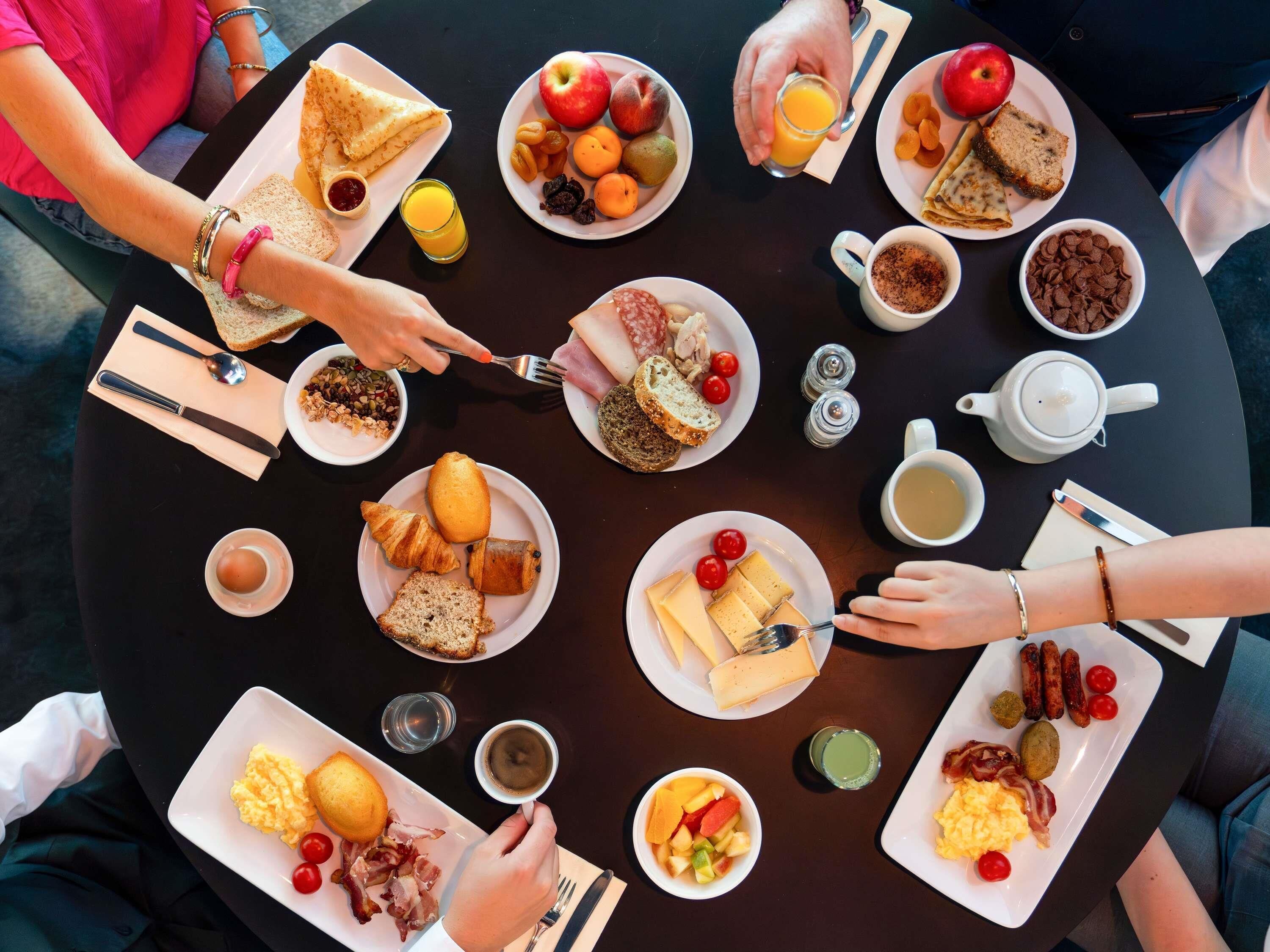 A round table with various breakfast items including toast, fruit, eggs, and sausages.