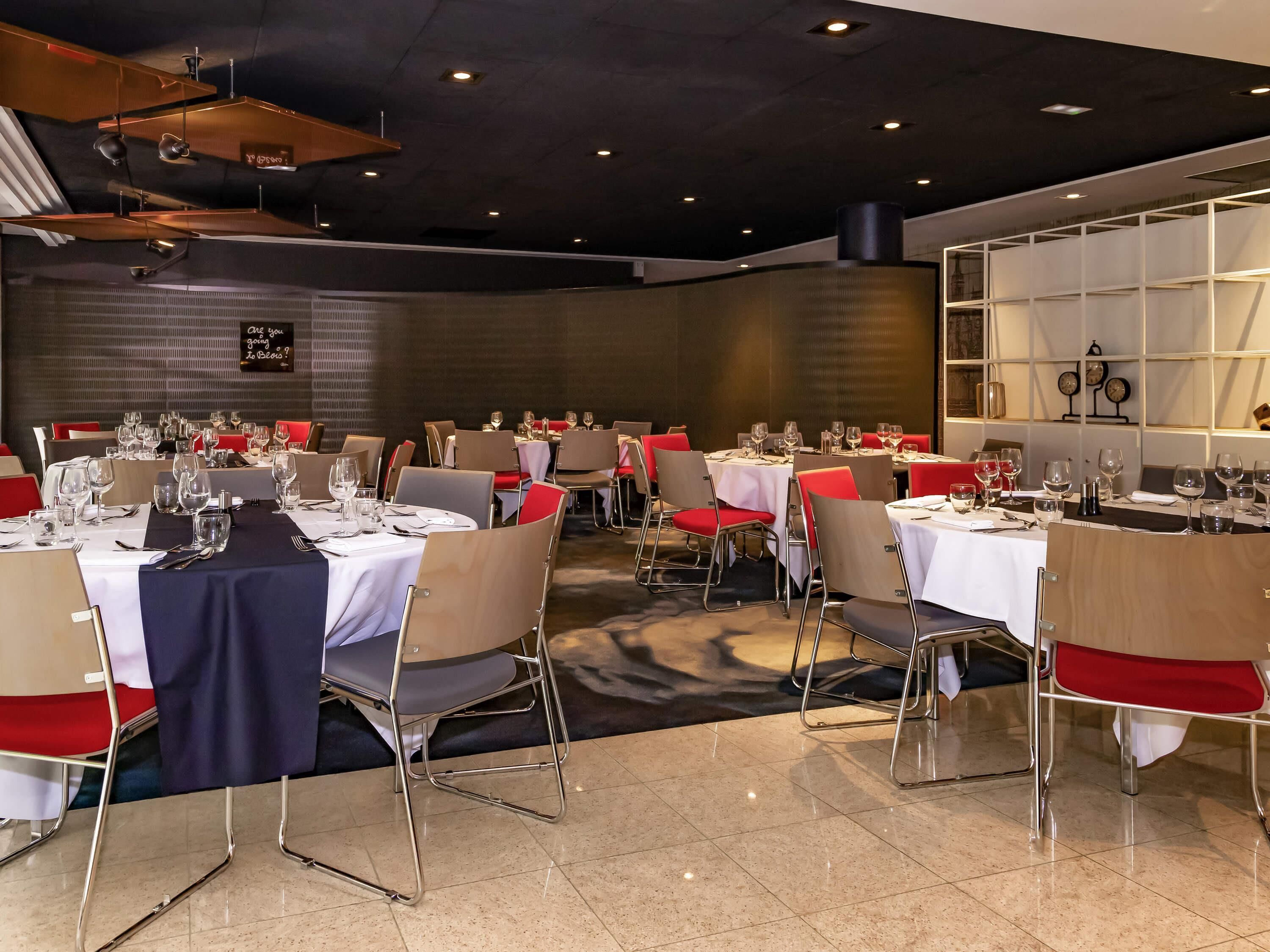 A restaurant with multiple tables, chairs, and a modern ceiling design.