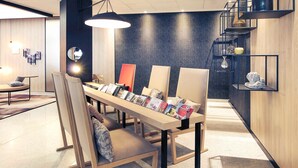 Una habitación moderna y bien iluminada con una mesa larga que exhibe revistas, asientos cómodos y una pared de diseño oscuro.