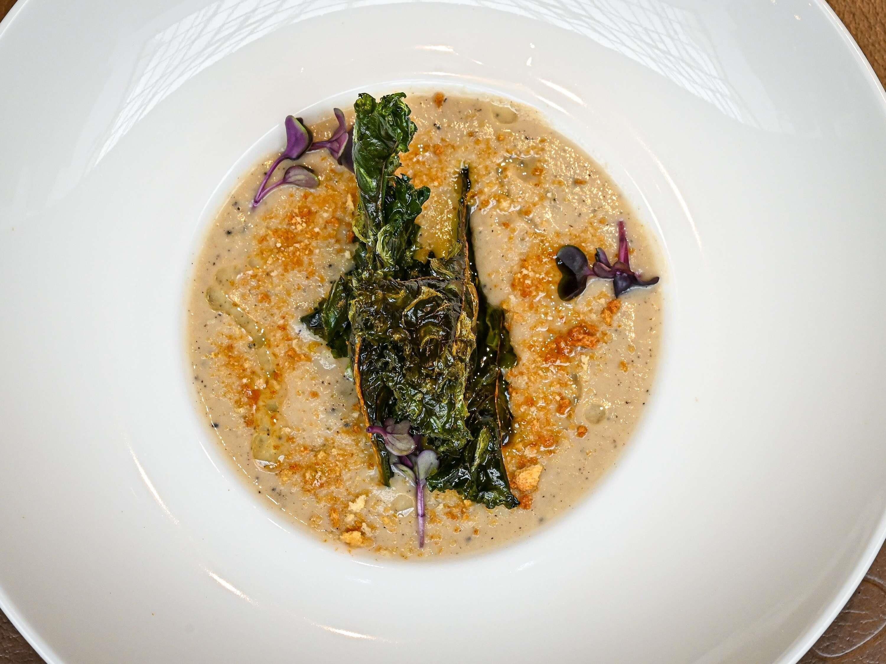 Une assiette blanche contenant une portion de légumes verts et une sauce crémeuse.