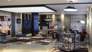 Un moderno vestíbulo de hotel con zona de estar, mostrador de recepción y un amplio ventanal.