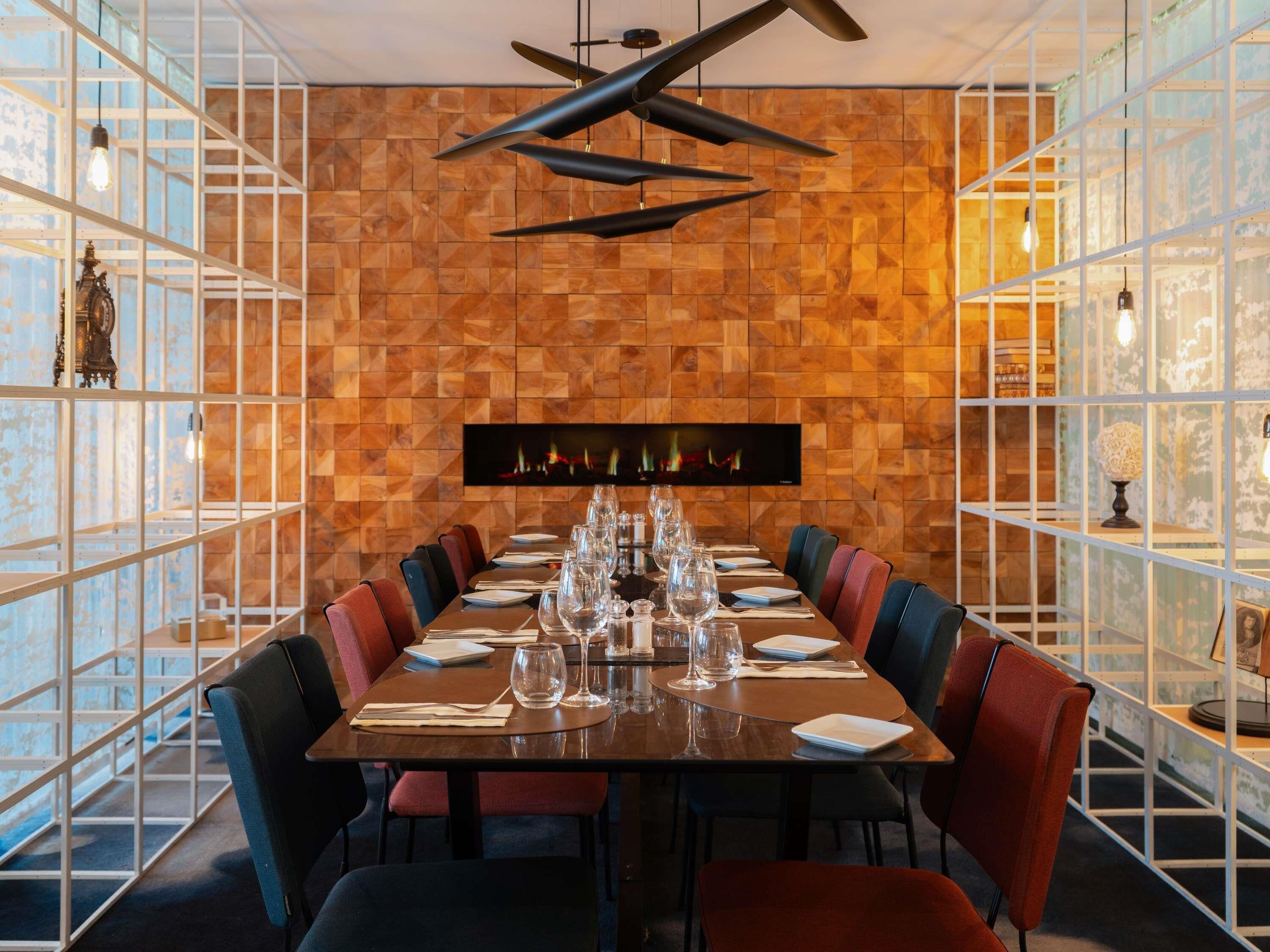 A dining area with a long table set for multiple guests, flanked by chairs with cushioned seats.