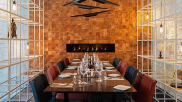A dining area with a long table set for multiple guests, flanked by chairs with cushioned seats.