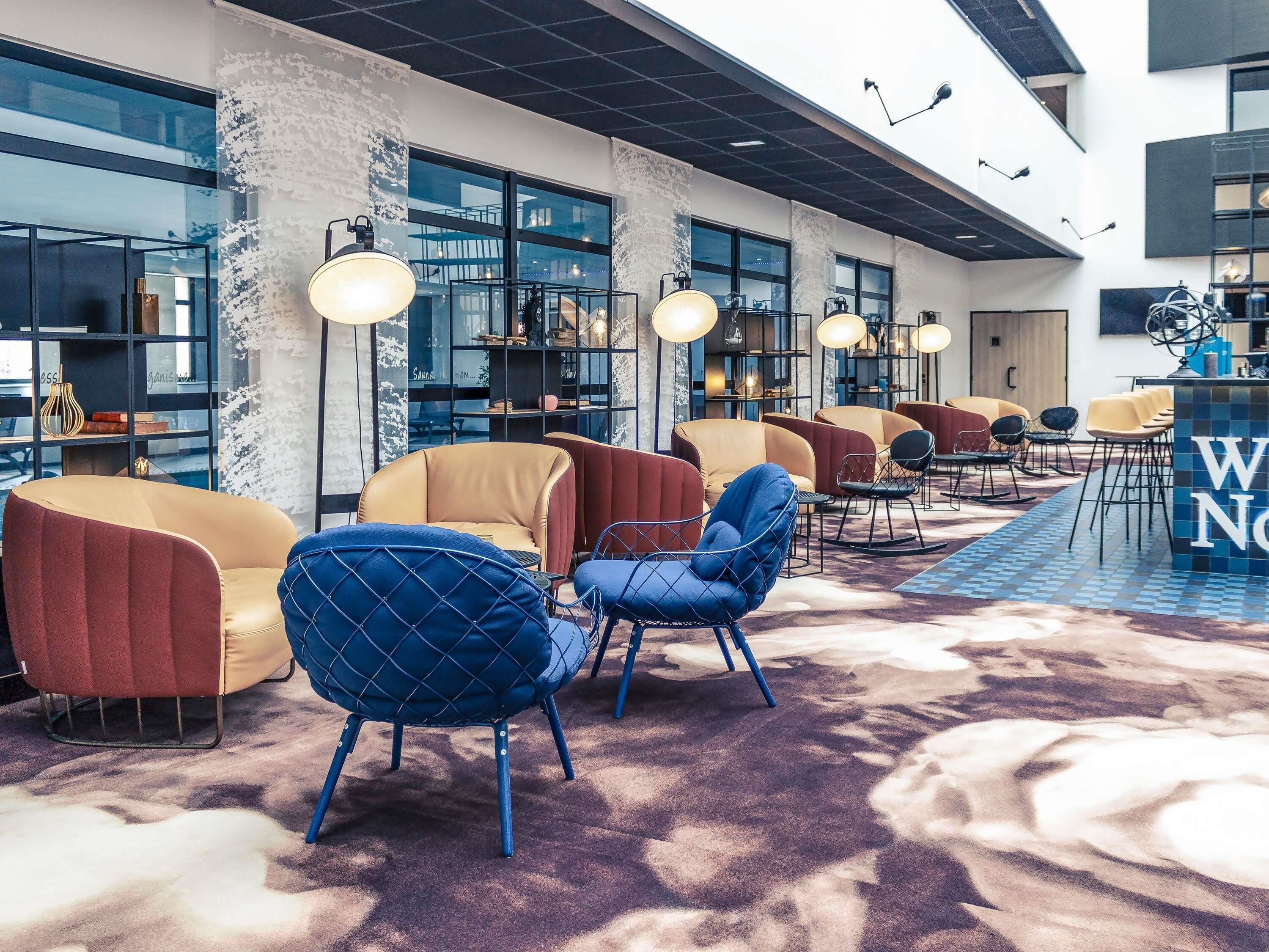 Un espace détente moderne, doté de sièges confortables, de grandes fenêtres et d’un tapis à motifs.