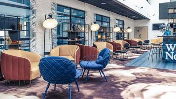 Un espace détente moderne, doté de sièges confortables, de grandes fenêtres et d’un tapis à motifs.