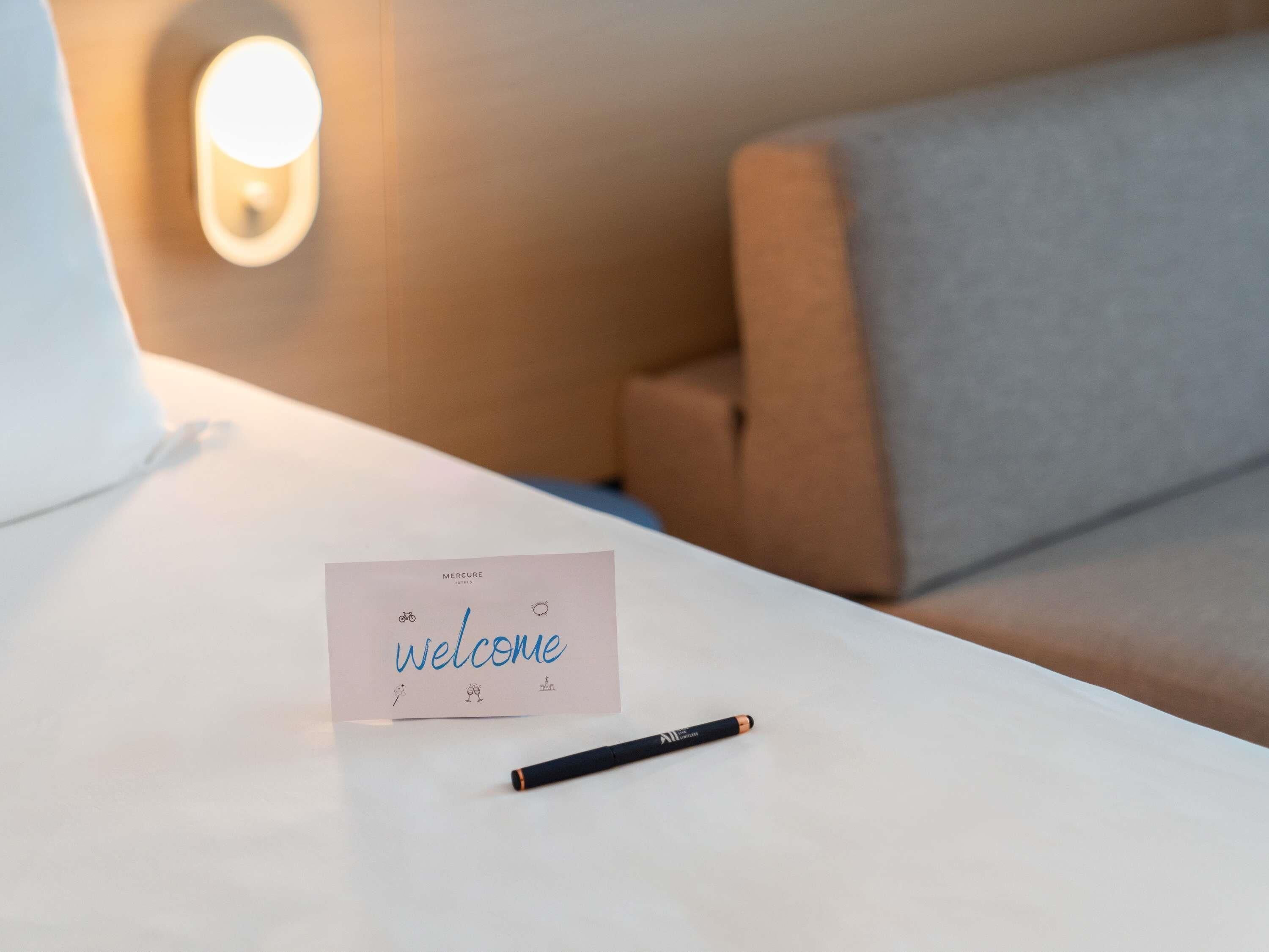 Une table blanche avec une carte de bienvenue et un stylo noir.