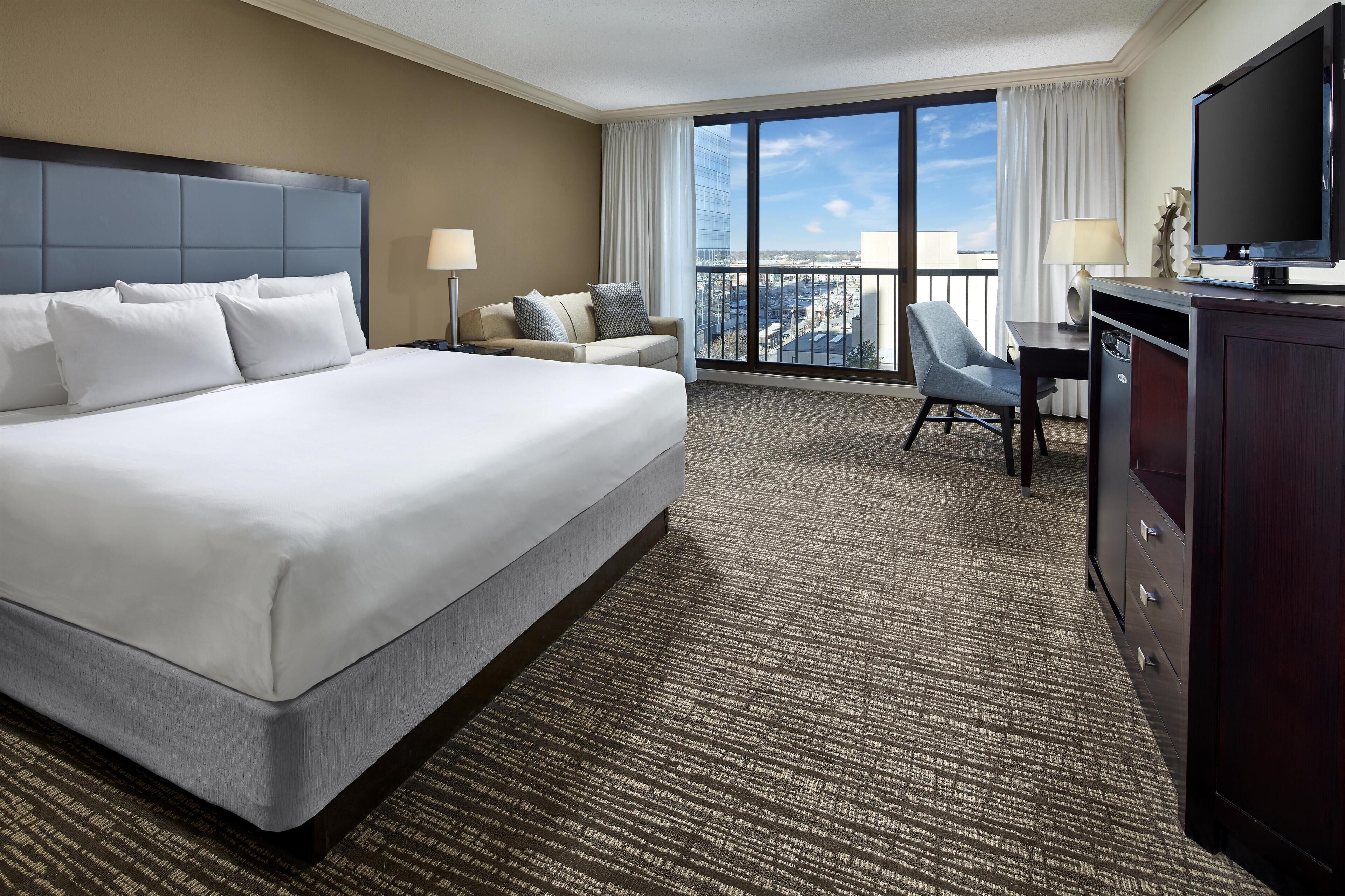 Une chambre d’hôtel avec un grand lit, un bureau, une chaise et un téléviseur.