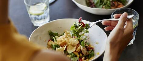 A person dining at a table with a bowl of salad and a glass of water.