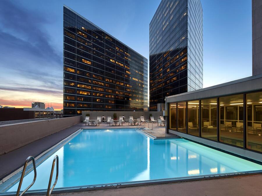 A rooftop pool with lounge chairs and a view of modern buildings.