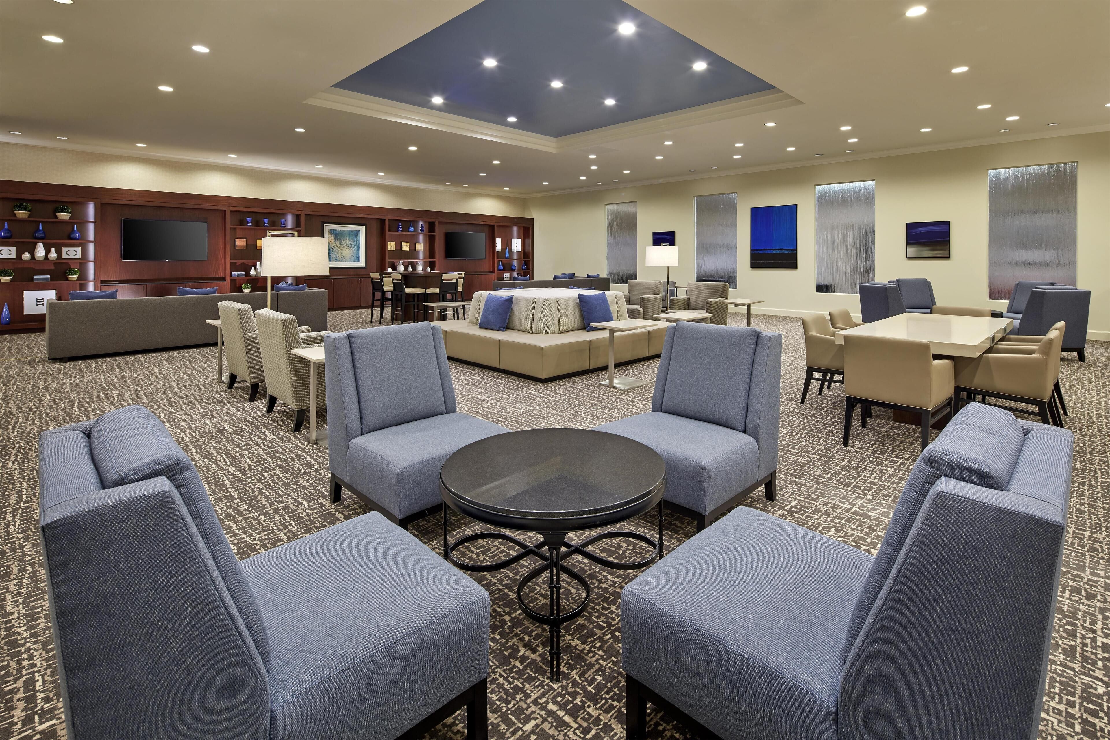 A hotel lobby with a seating area, a TV, and a bar.