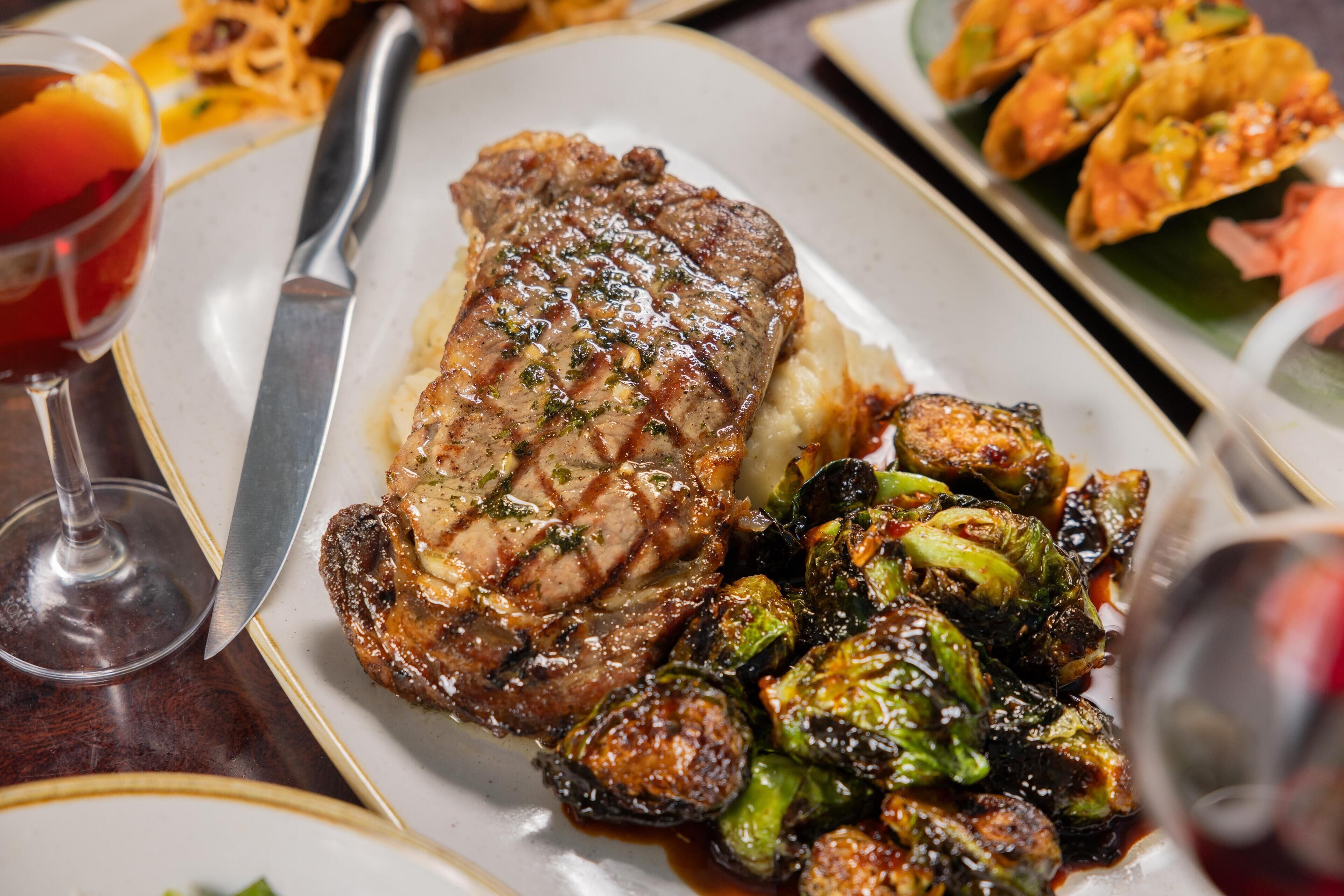 Un plato con un bistec, puré de papas y brócoli belga asado.