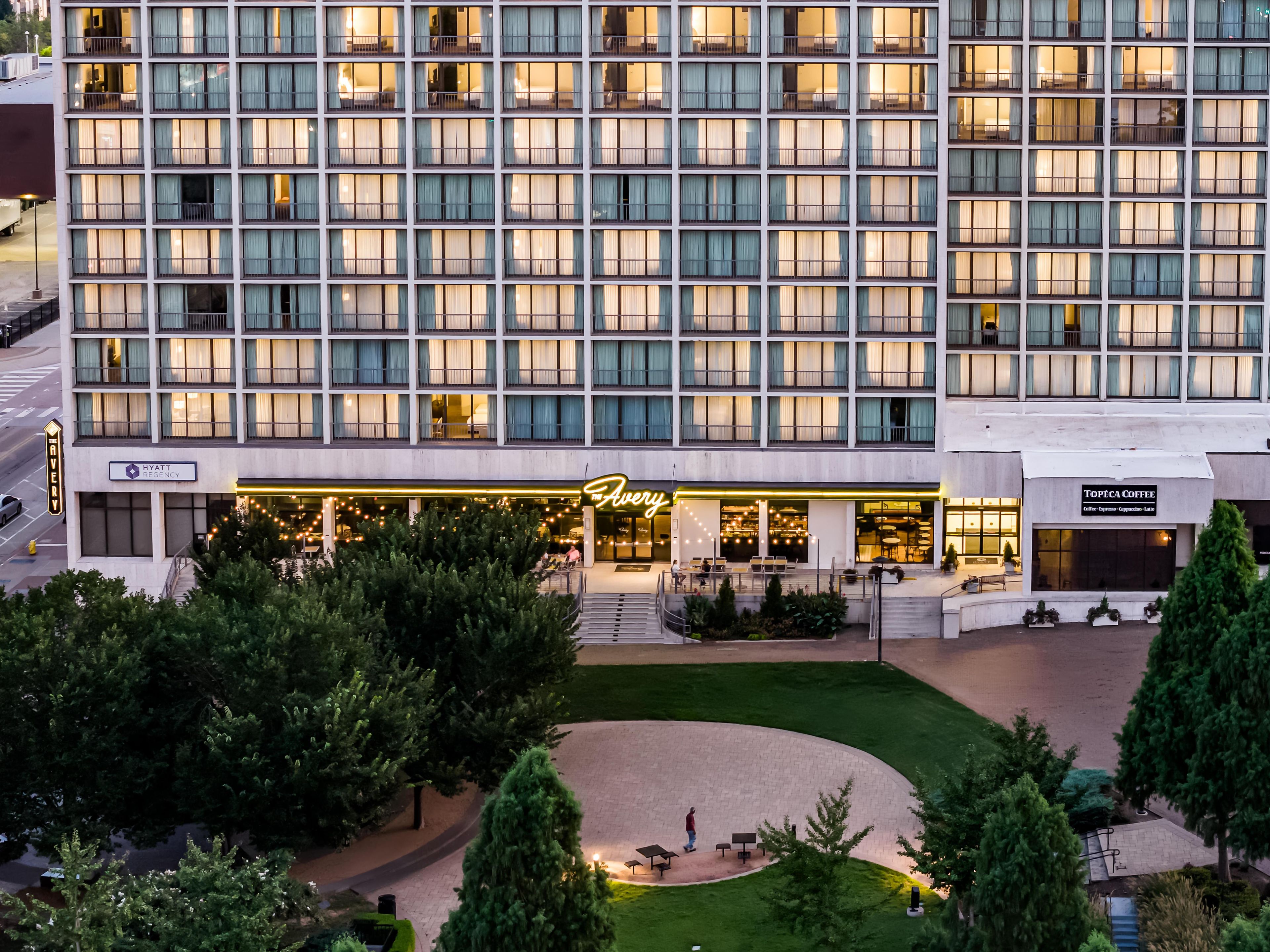A multi-story hotel with a modern facade, a well-lit entrance, and a landscaped courtyard.