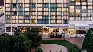 A multi-story hotel with a modern facade, a well-lit entrance, and a landscaped courtyard.