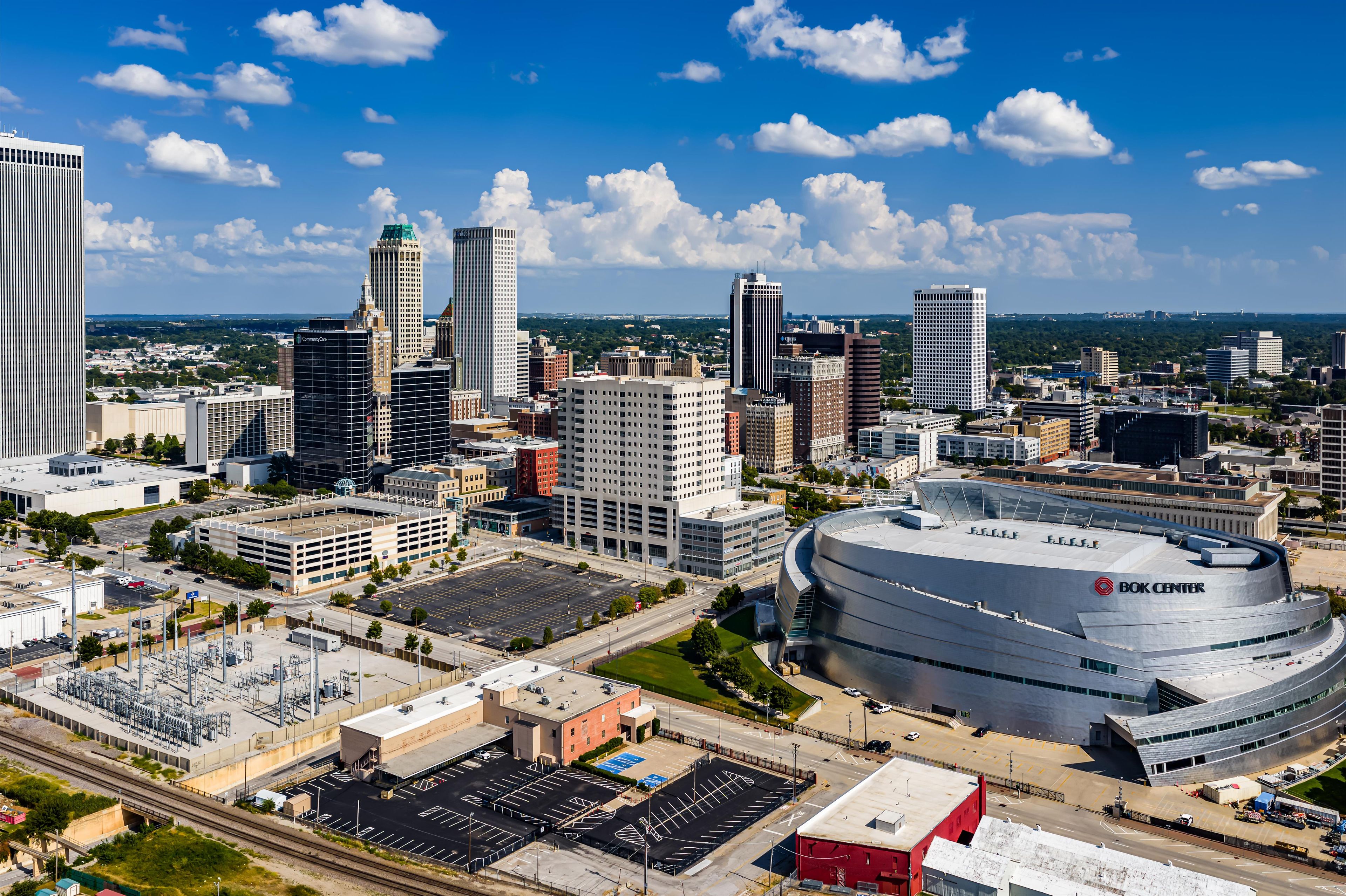 A cityscape with a prominent BOK Center stadium, surrounded by various buildings and a parking area.