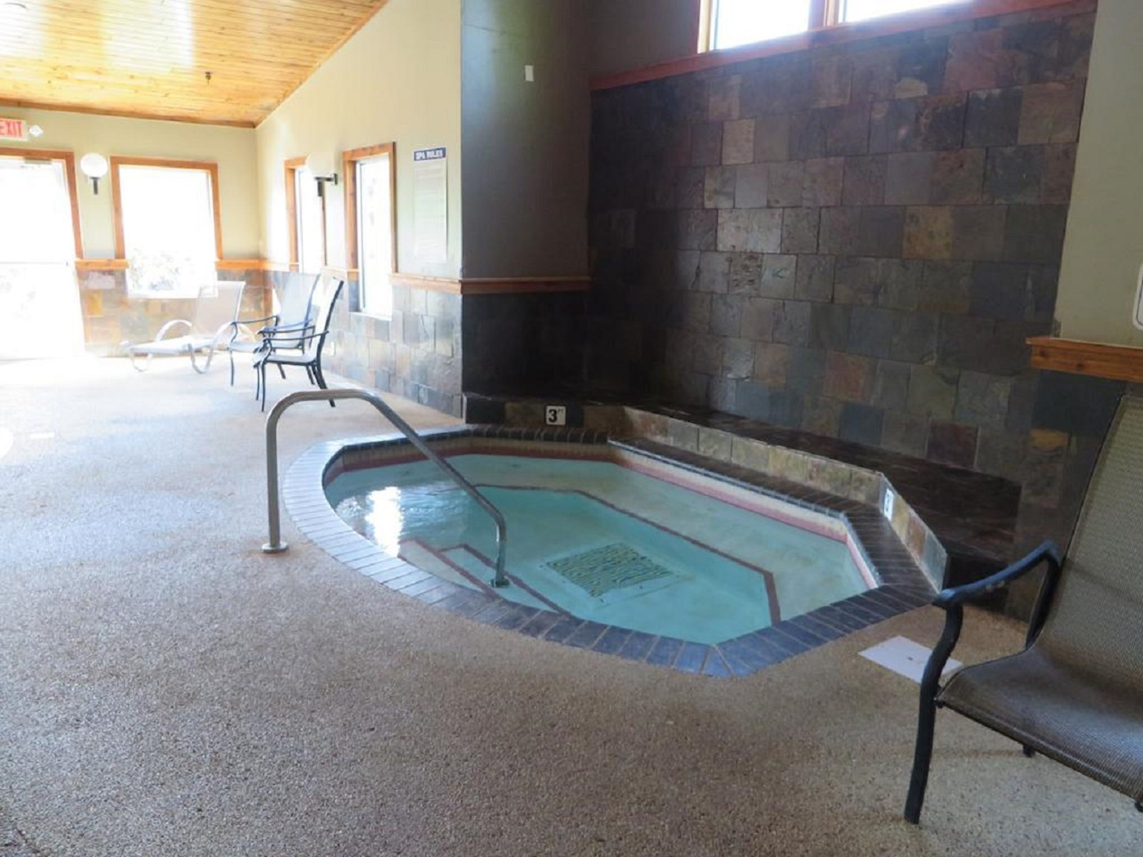 A pool area with a stone wall and a bench.