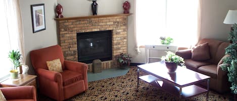 A living room with a fireplace, a clock, and a patterned carpet.