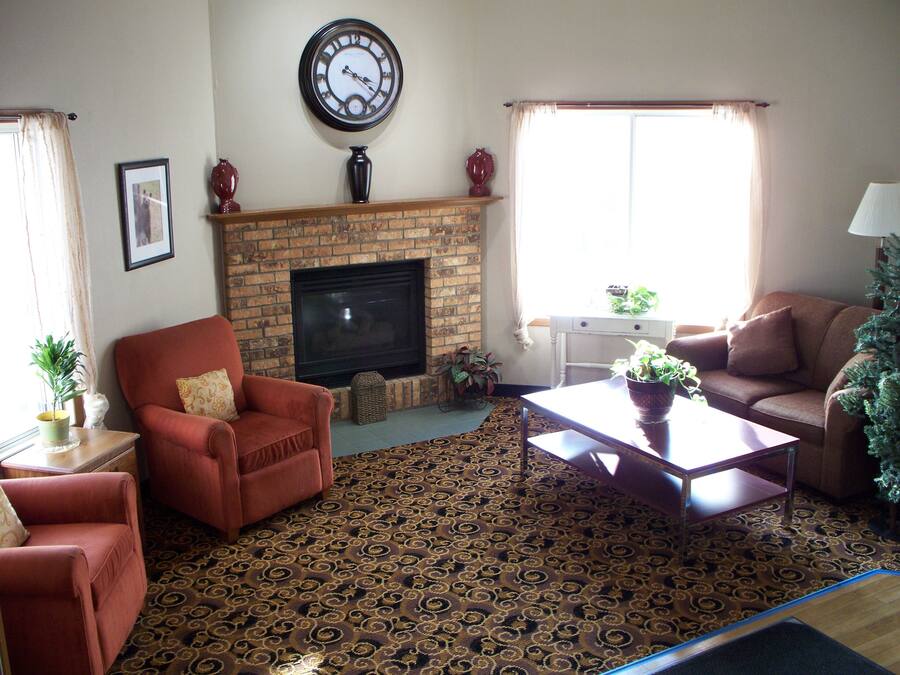 A living room with a fireplace, a clock, and a patterned carpet.