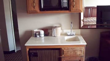 Una kitchenette compacta con microondas, pileta y un mueble pequeño.