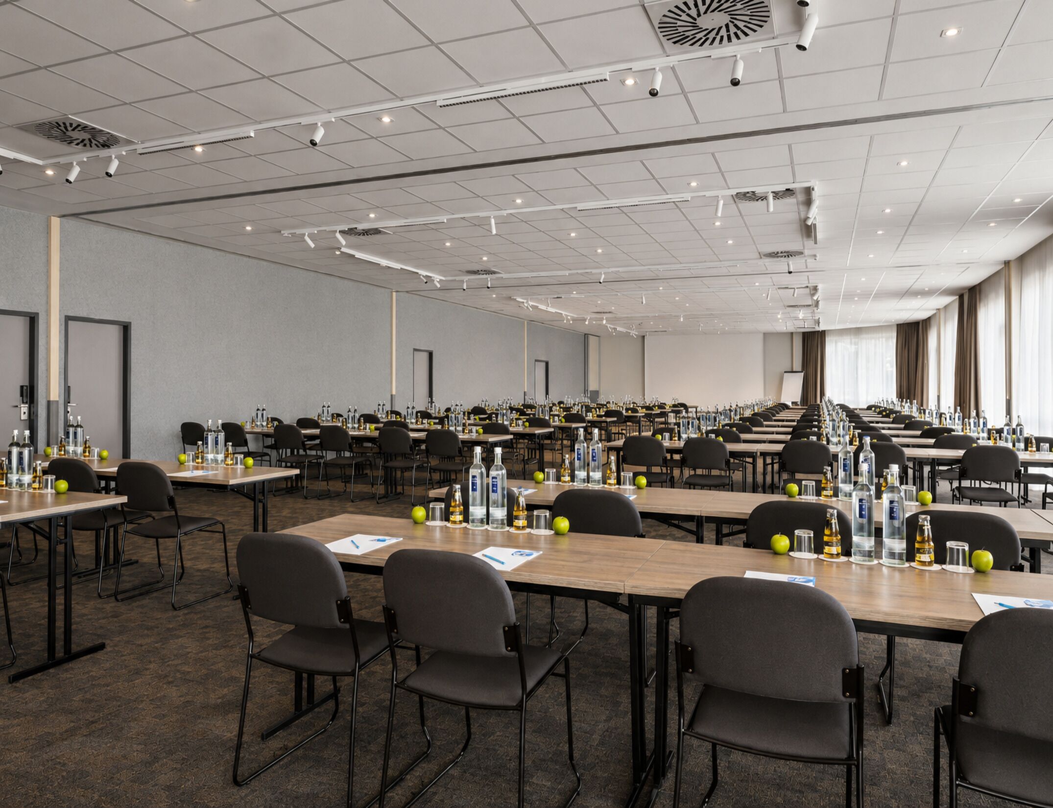 A conference room with multiple tables, chairs, and water bottles.