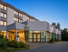 Un hotel moderno con fachada plana, amplias ventanas y un jardín bien cuidado.