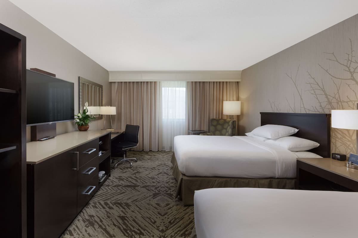 A hotel room with a bed, a desk, a TV, and a chair.