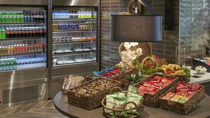 A self-service food station with refrigerated beverages, snacks, and fresh produce. - Hilton Cincinnati Airport (Florence)