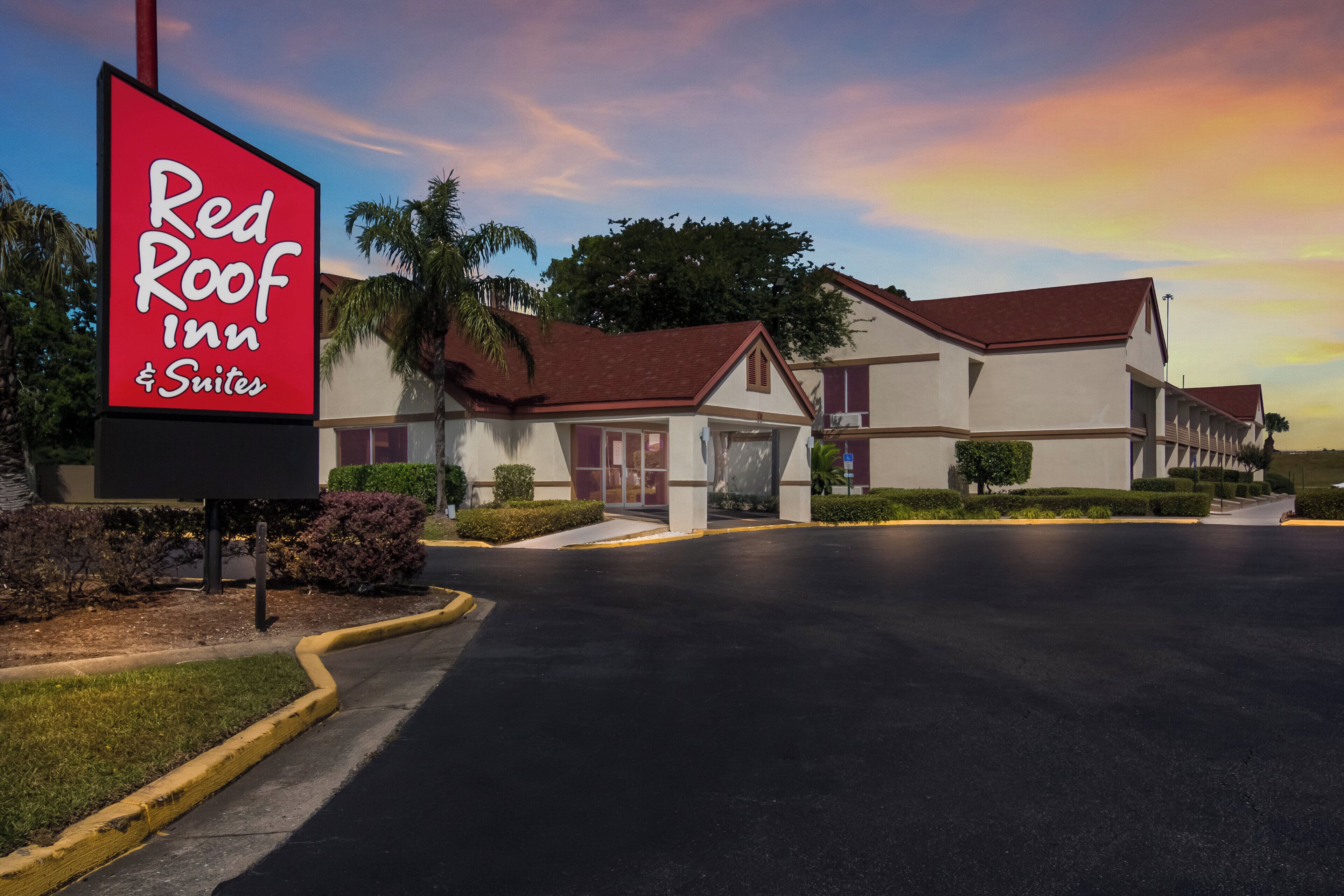 A Red Roof Inn & Suites with a clear sky and a well-maintained parking lot.