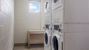 Ein Waschraum mit übereinander gestapelten Waschmaschinen und einem kleinen Fenster.
