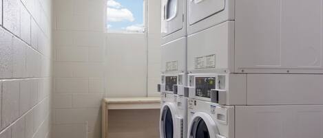 A laundry room with stacked washing machines and a small window.