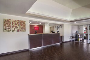 A reception area with a wooden reception desk, a red sign indicating free Wi-Fi, and framed certificates on the wall. - Red Roof Inn & Suites Brunswick I-95 (Brunswick)