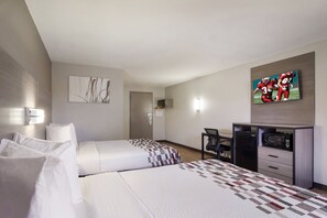Two single beds with white linens and a patterned bedspread, a flat-screen TV, and a desk with a chair.